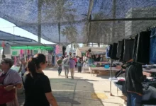 Personas caminando entre puestos al aire libre bajo toldos en el Mercadillo Navideño de Cádiz.