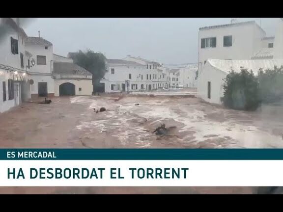 Plaza y calles de Es Mercadal inundadas por la crecida del torrente que afecta la zona de la Feria de Segunda Mano, Antigüedades y Coleccionismo de Es Mercadal.