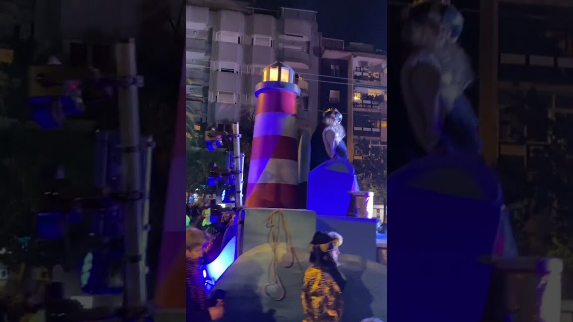Carroza con faro iluminado y participantes en desfile nocturno de la Feria de Navidad de Esplugues de Llobregat
