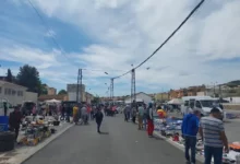 Personas recorriendo puestos al aire libre en el Mercadillo Navideño de Baza en una amplia calle urbana.