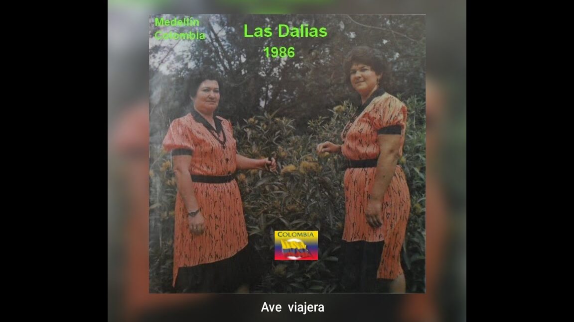 Dos mujeres con vestidos a juego frente a vegetación y bandera de Colombia, evocando el Mercadillo Navideño de Las Dalias