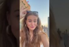 Joven sonriente con gafas sobre la cabeza frente al Mercadillo de Ciutadella al atardecer