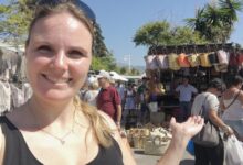 Mujer sonriente en el Mercadillo de Puerto Banús frente a puestos de bolsos, cestas y ropa
