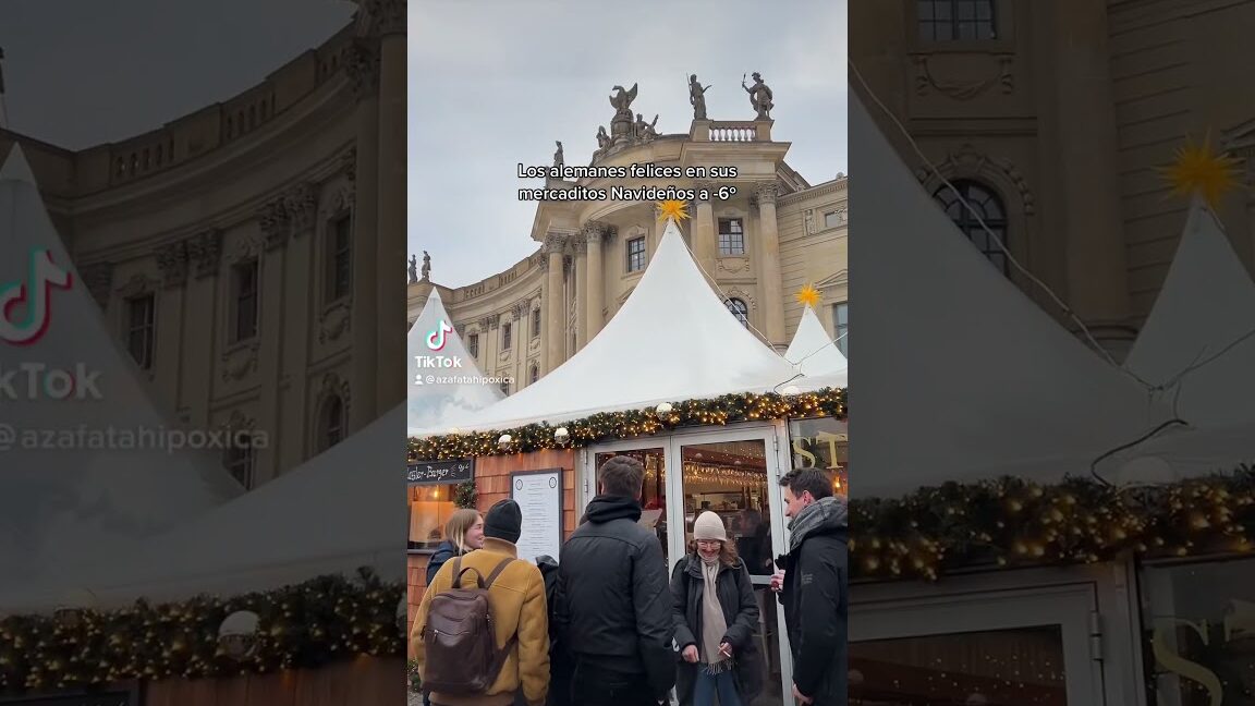 Visitantes abrigados junto a casetas decoradas en el Mercadillo Navideño de Teror bajo carpas blancas
