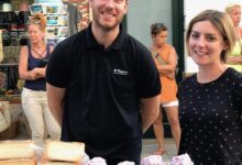 Vendedores sonrientes en un puesto de quesos en el Mercadillo Nocturno de Es Mercadal.