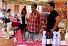 Puesto de vinos y degustación en el Mercat de la Terra de Xaló con copas, decantador y botellas sobre mesa roja.