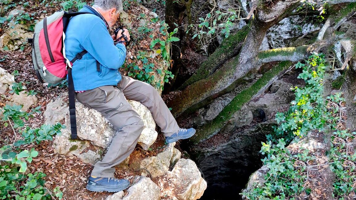 Fotógrafo sentado en una roca junto a una grieta profunda en el bosque, Feria de Navidad de Olesa de Bonesvalls