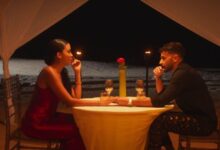 Pareja en cena romántica junto a la playa con velas y flor en la mesa en el Mercadillo de Santa Maria del Camí