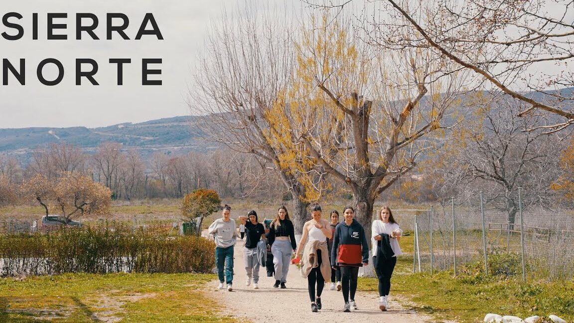 Grupo de personas caminando por un sendero rural entre árboles y montañas en la Feria De Productos Típicos Y Artesanales De La Sierra Norte