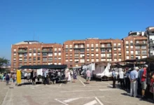 Mercado de Aldeanas de Portugalete con puestos al aire libre, ropa colgada y compradores paseando bajo un cielo azul